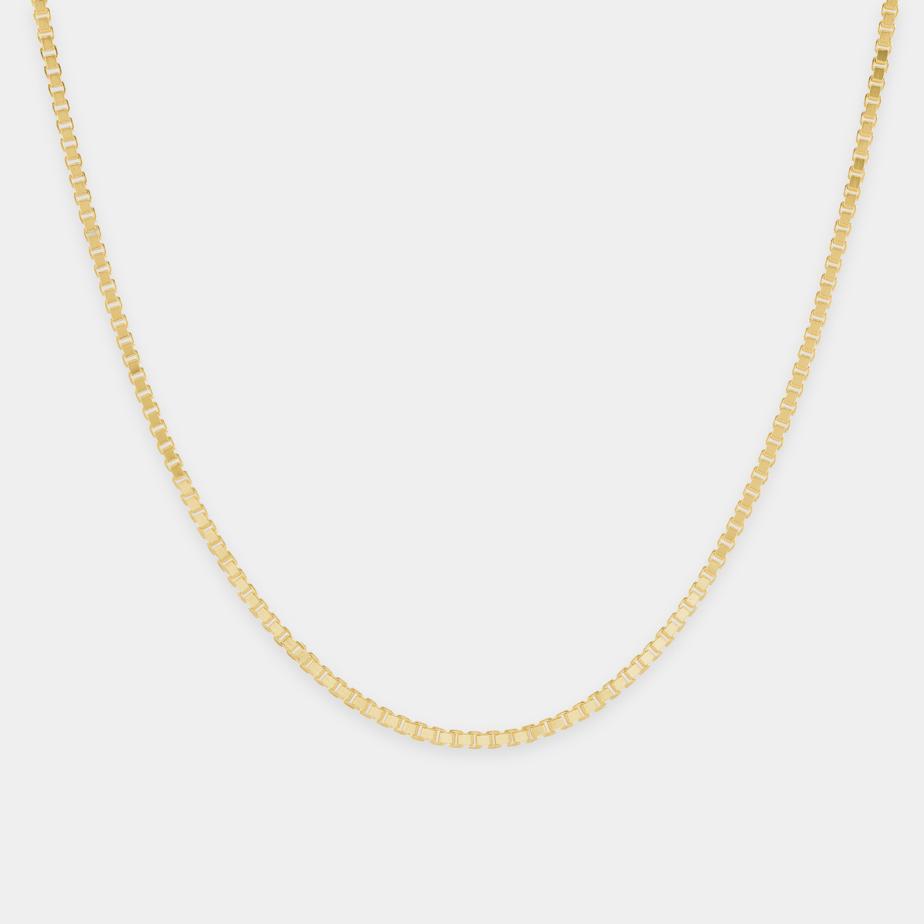 Gold chain necklace on a light gray background.